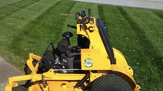 A yellow lawn mower is sitting on top of a lush green lawn.