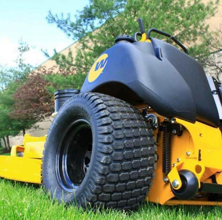 A yellow and black lawn mower is parked in the grass