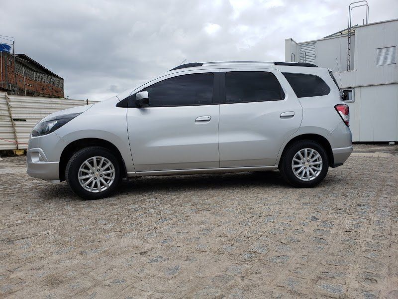 Um SUV prateado está estacionado em um estacionamento de cascalho.