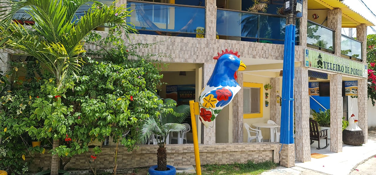 Um balão azul em forma de galo está em um poste em frente a um prédio.