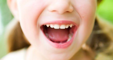 a small girl showing her teeth