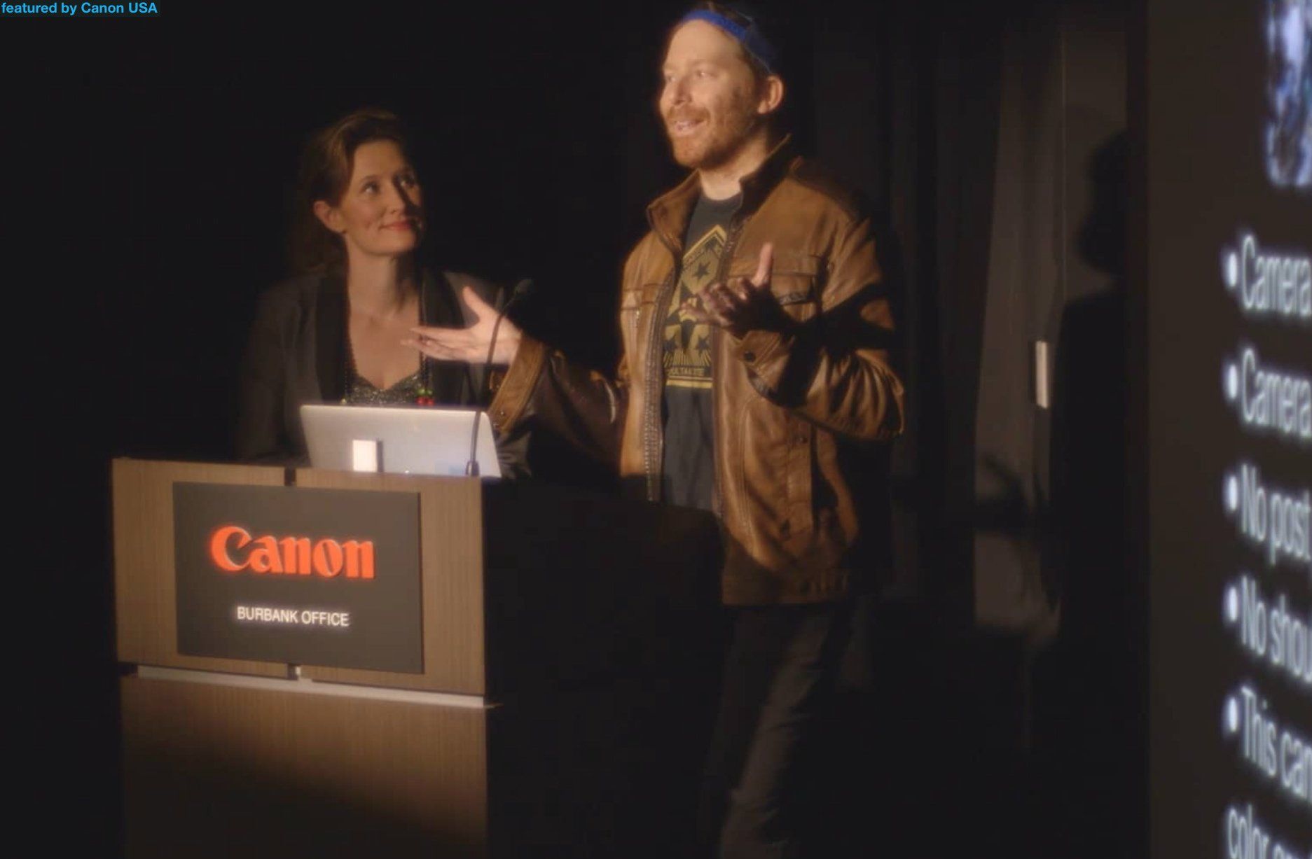 A man is giving a presentation in front of a canon podium