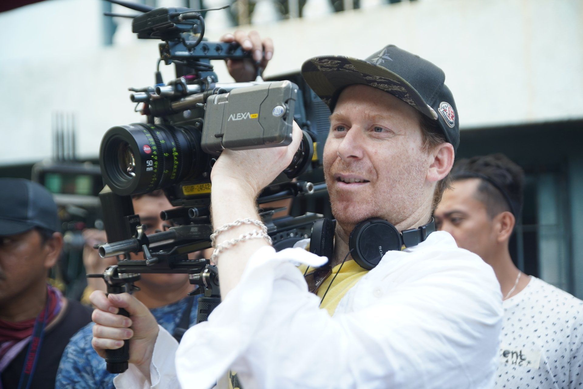 A man in a hat is holding a camera in his hand.