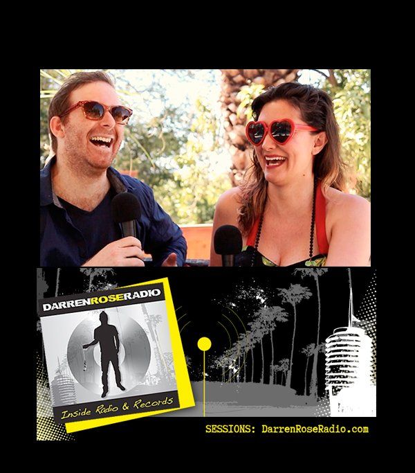 A man and a woman are laughing in front of microphones