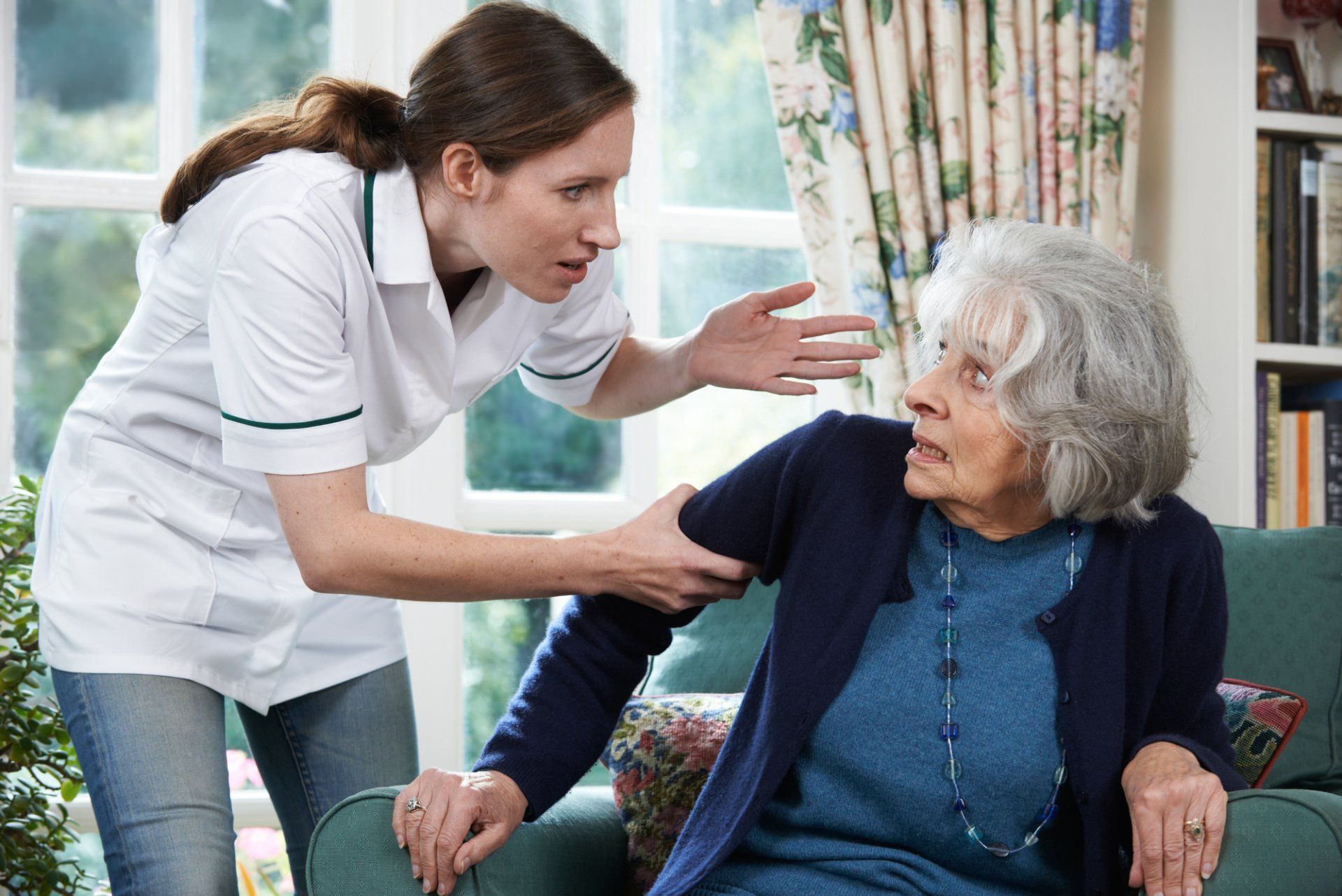 Nurse scolds elderly woman, grabbing her arm indoors.