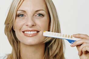 Woman holding up tooth whitening chart — Dental Services in Griffith, IN Woman holding up tooth whitening chart — Dental Services in Griffith, IN