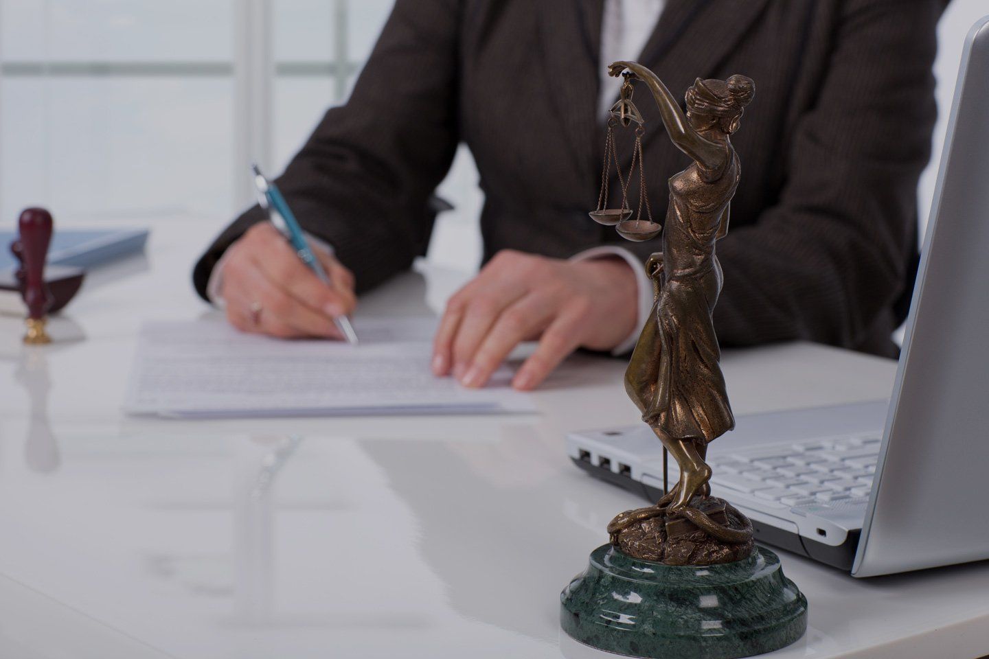 Avvocato durante la stesura di un contratto e statua della giustizia
