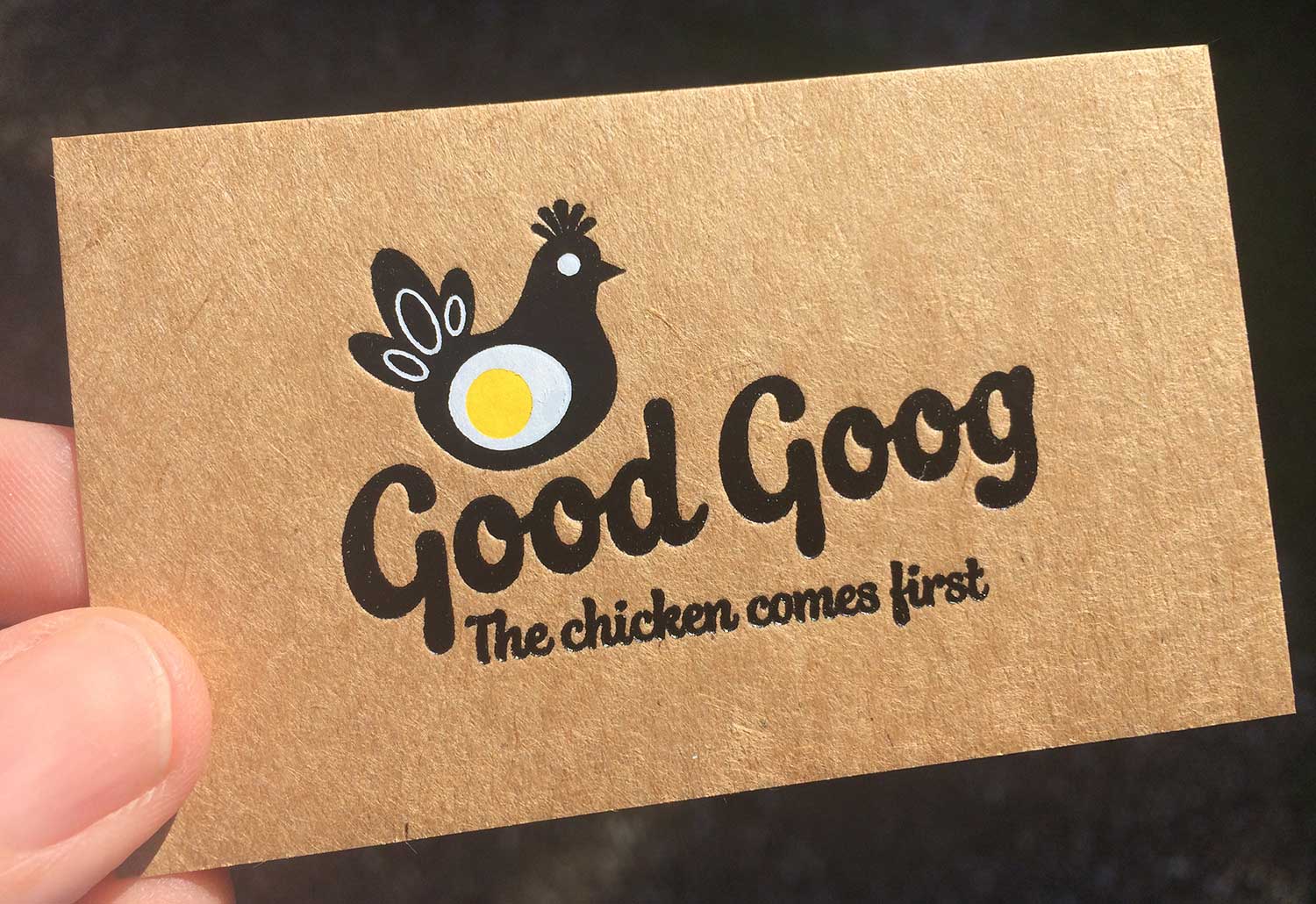 A person is holding a business card for Good Goog