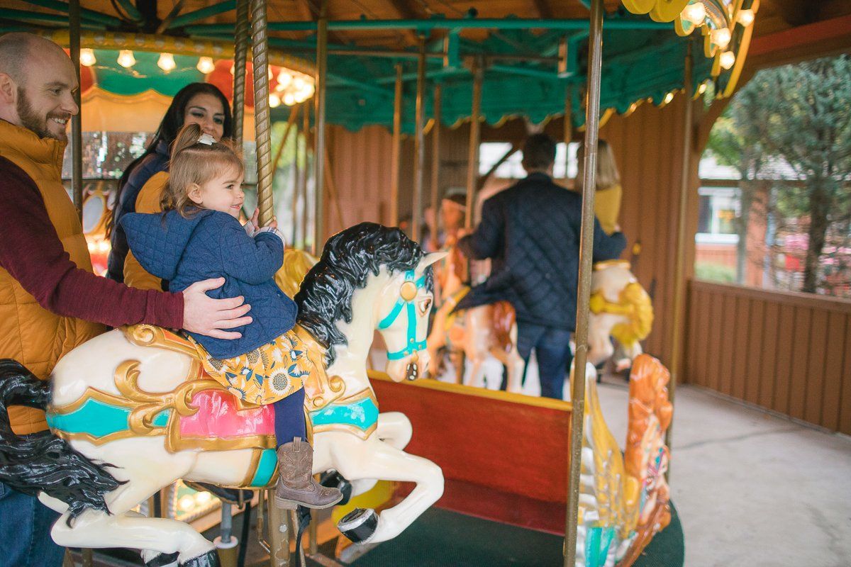 A family is riding a merry go round at an amusement park