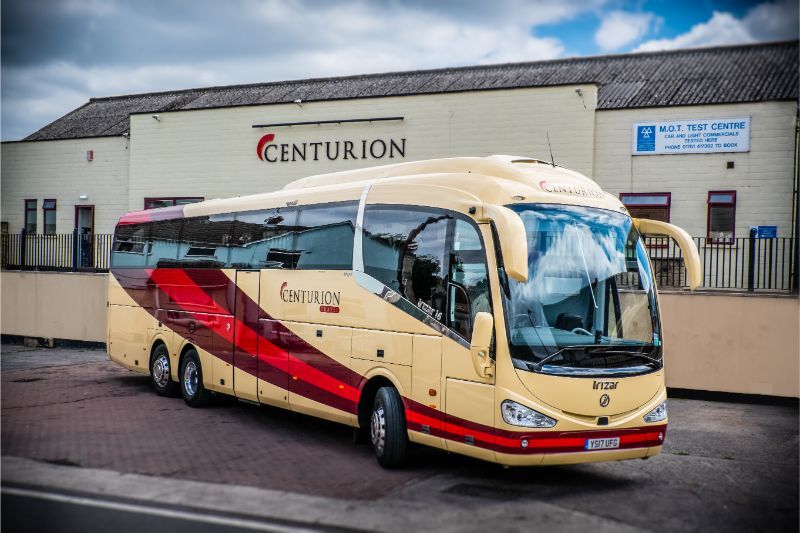 A centurion bus is parked in front of a building