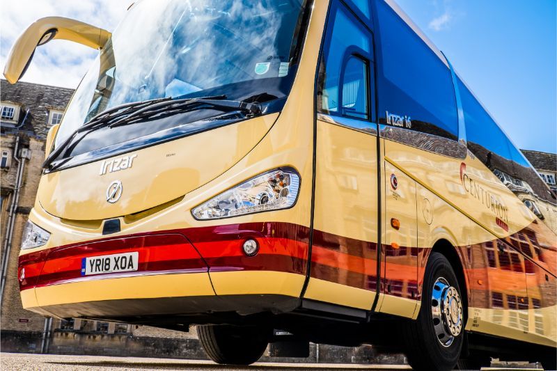 A yellow and red bus is parked on the side of the road.