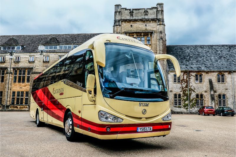 A yellow and red bus is parked in front of a building.
