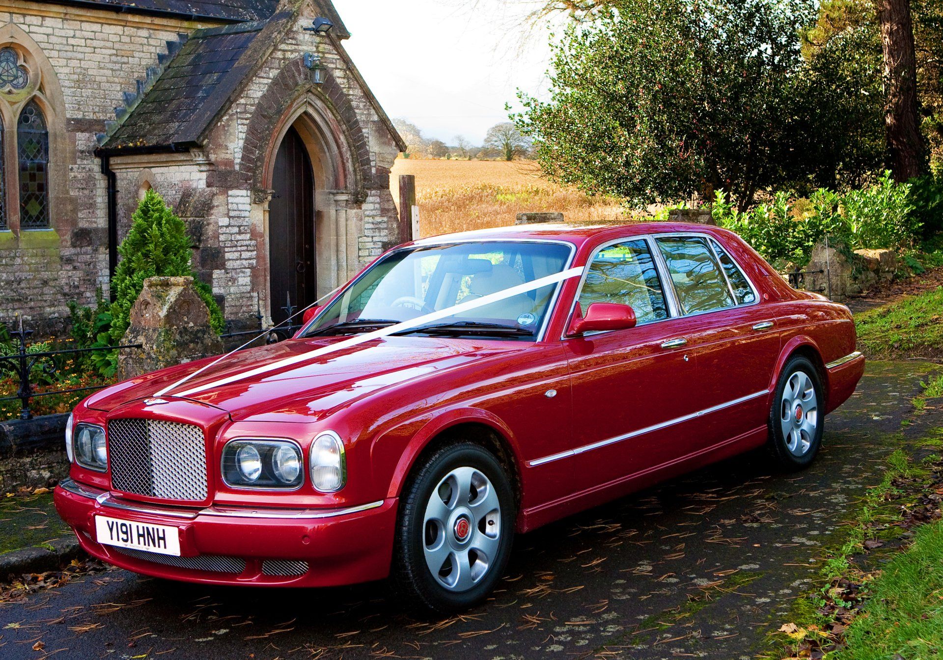 A red car is parked in front of a church.