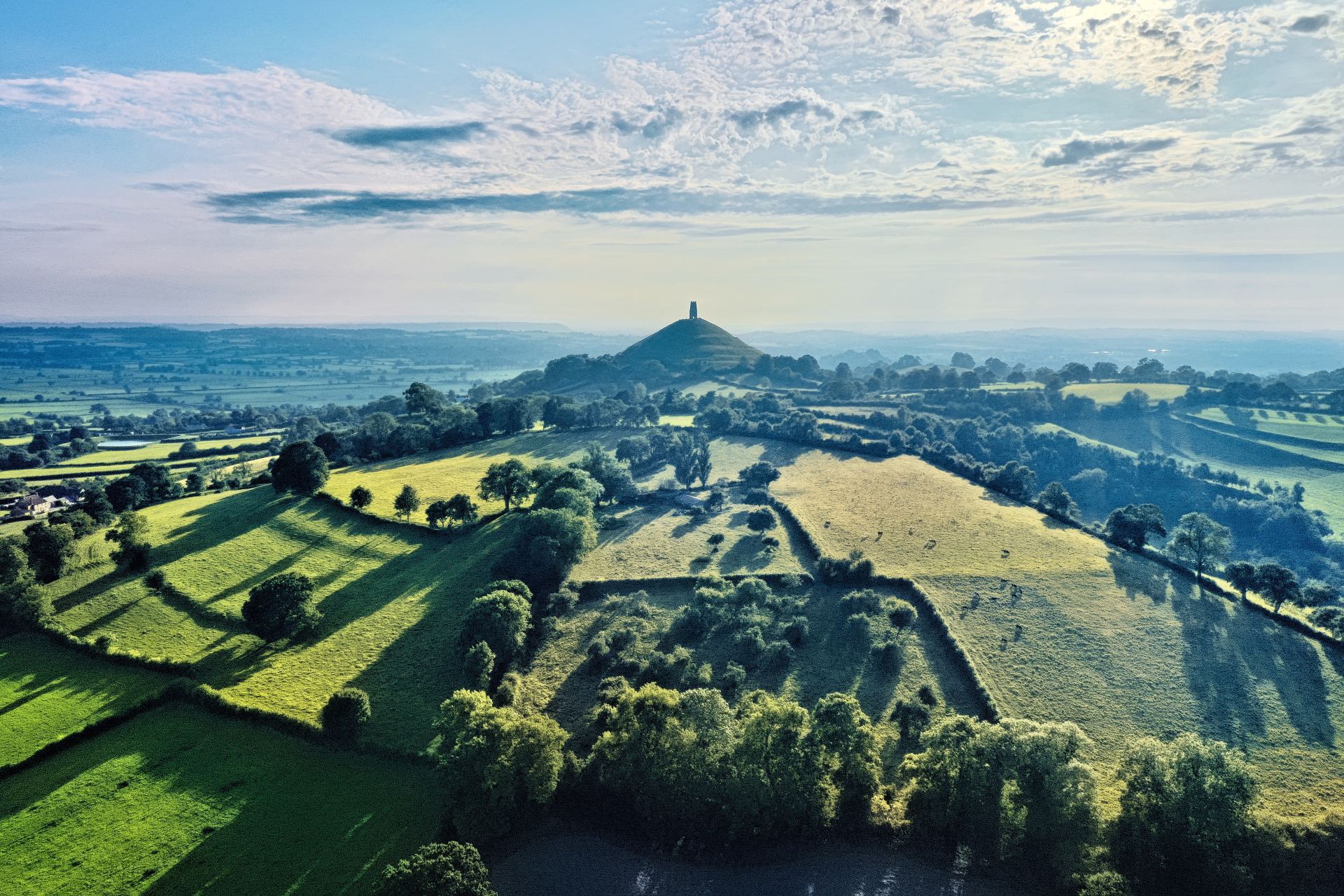 An aerial view of a lush green hillside with a castle in the distance.