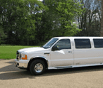 A white limousine is parked on the side of the road.