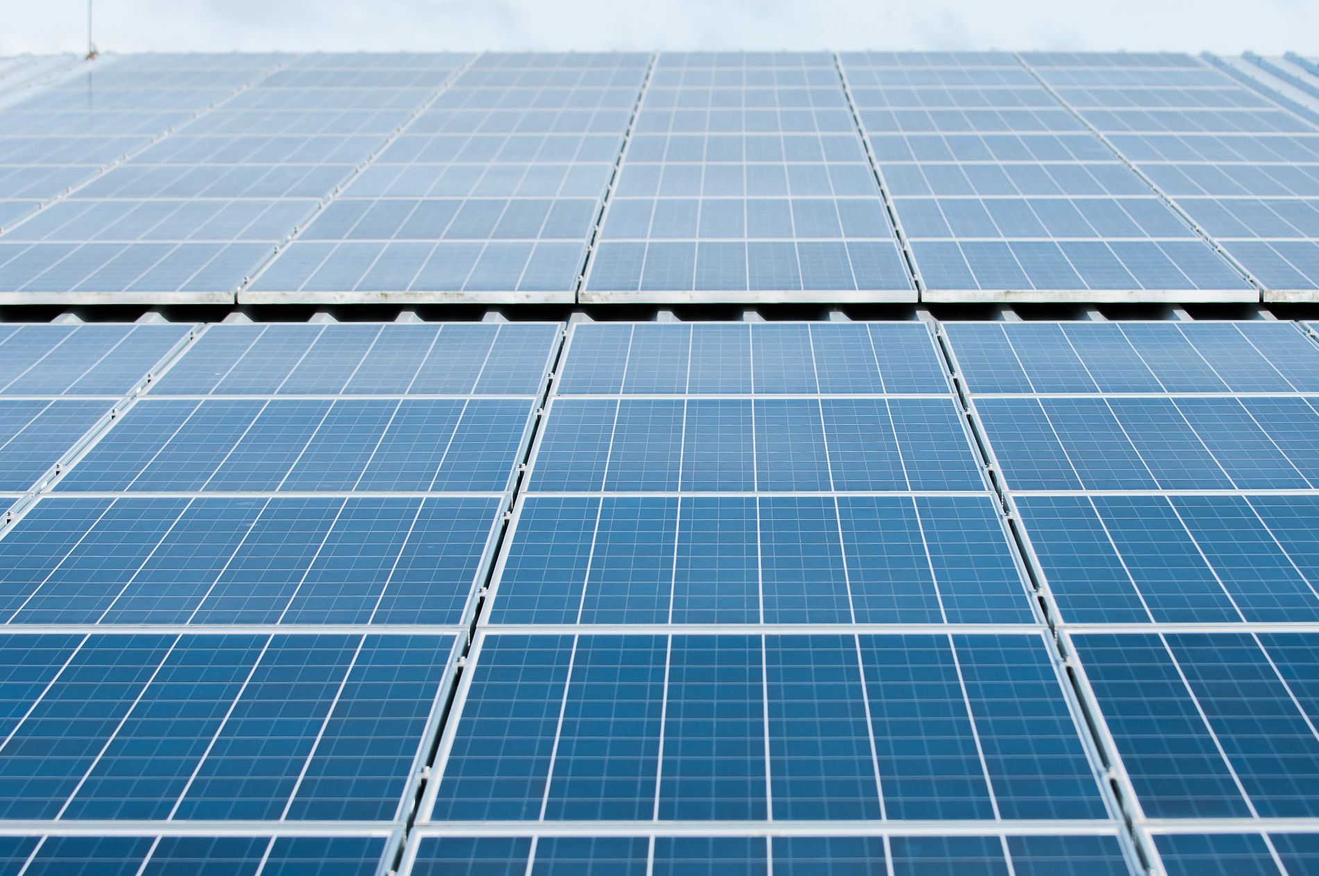 Solar panels on a roof, blue squares in a grid, generating green energy.