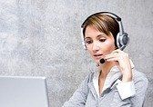 Woman wearing a headset working on a laptop, likely in a call center.