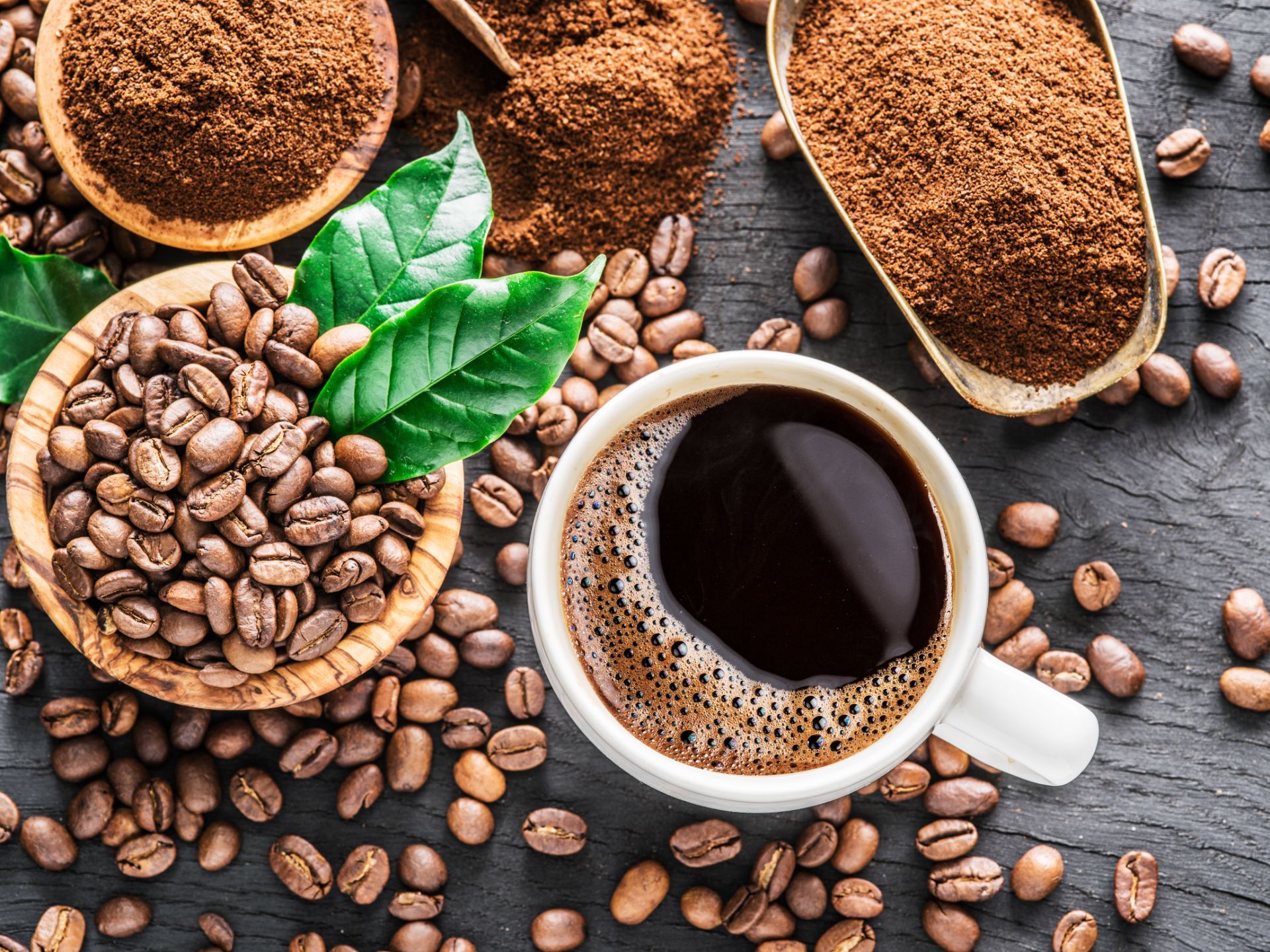 tazza di caffè e diverse qualità di caffè macinato e in grani