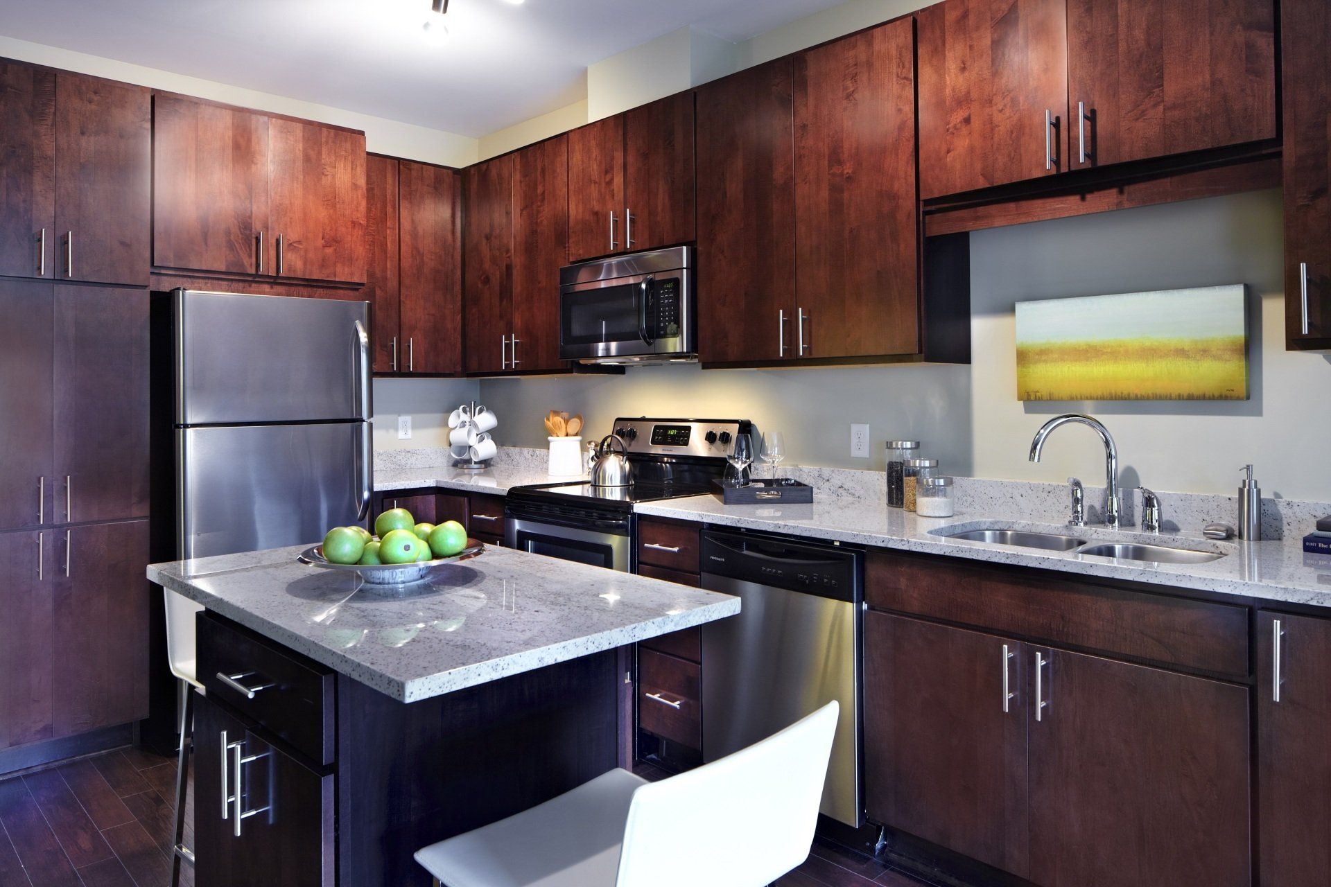 A kitchen with stainless steel appliances and wooden cabinets at 222 Hennepin Apartments.