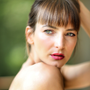 Woman with bangs looking at the camera, red lipstick, light skin, soft focus.