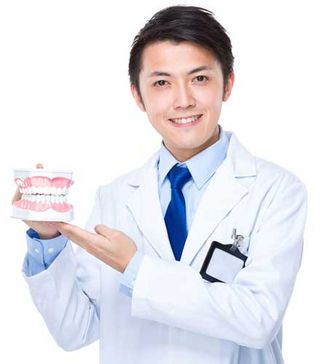 Dentist holding dentures — Family dentist in Forest Hills, NY