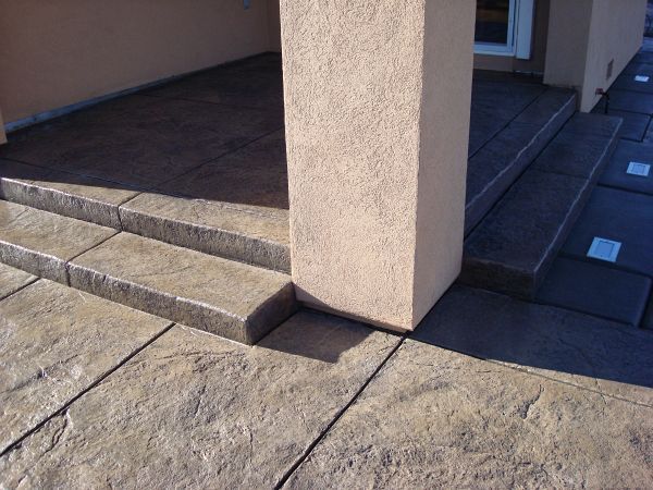 A concrete patio with steps and a pillar in the background