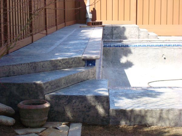 Stairs leading up to a swimming pool with a fence in the background