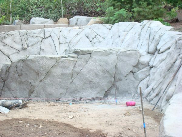 A large rock wall is being built in a garden