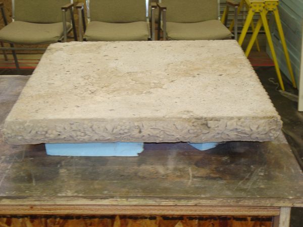 A square piece of concrete sits on a table in front of chairs