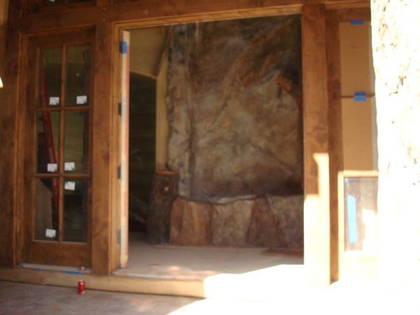 A wooden door is open to a stone fireplace