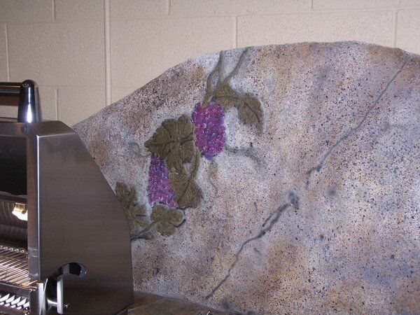 A painting of grapes on a wall next to a grill