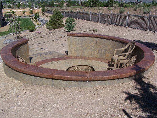 A fire pit with two chairs in the middle of it