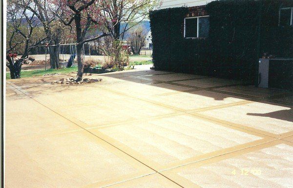 A concrete driveway with a house in the background