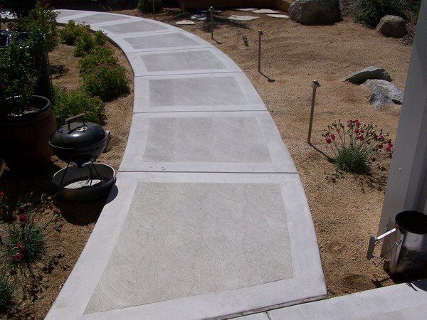 A concrete walkway with a grill on the side of it