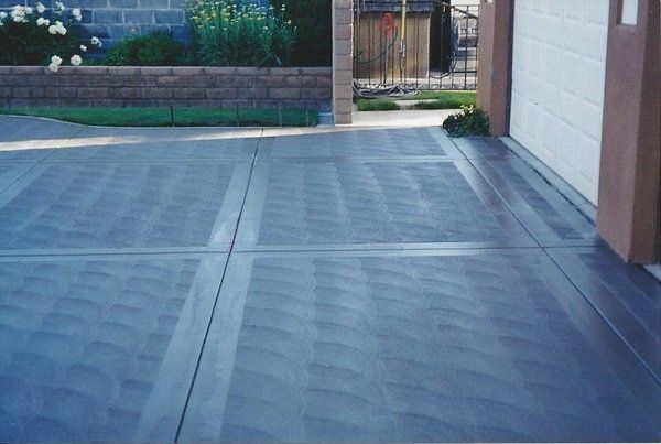 A concrete driveway with a white garage door in the background