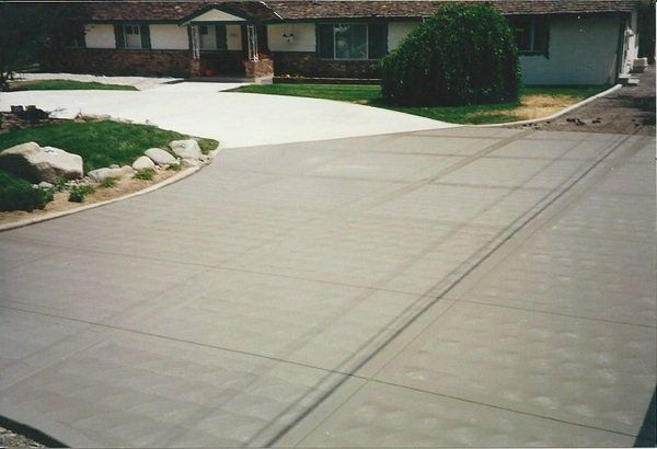 A concrete driveway with a house in the background
