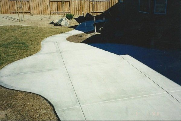 A concrete walkway with a wooden fence in the background