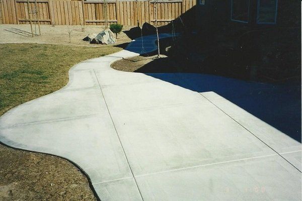 A concrete walkway with a wooden fence in the background