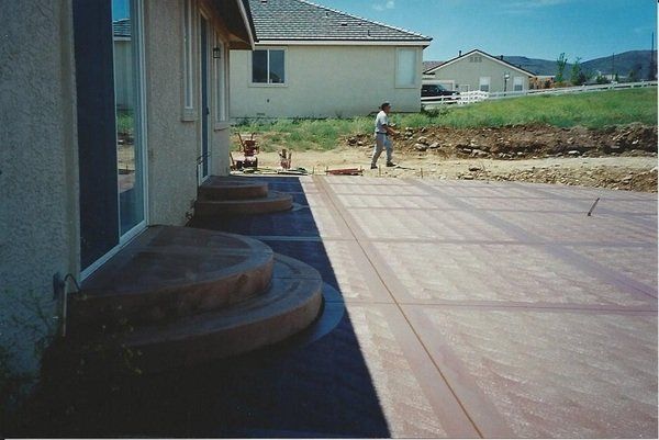 A man is standing on a concrete patio in front of a house