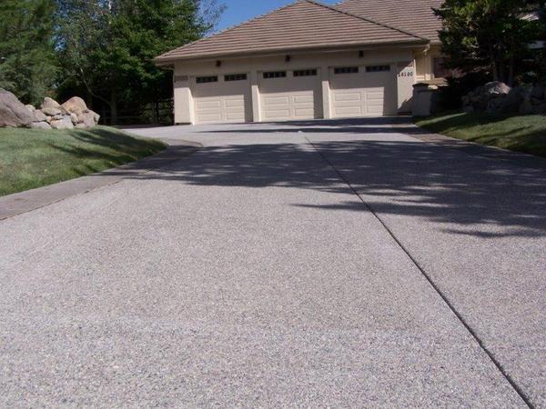 A driveway leading to a house with three garage doors