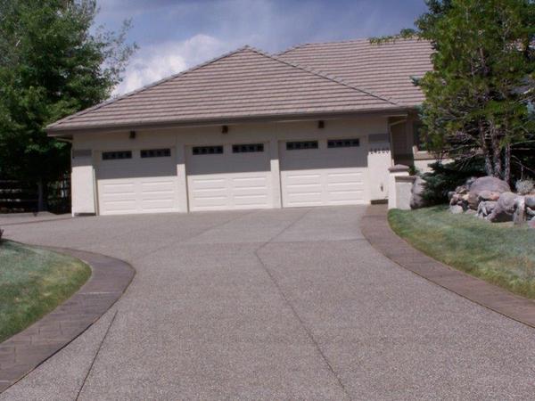 A driveway leading to a house with three garage doors