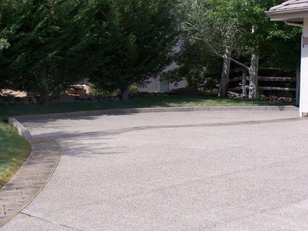 A driveway leading to a garage with trees in the background