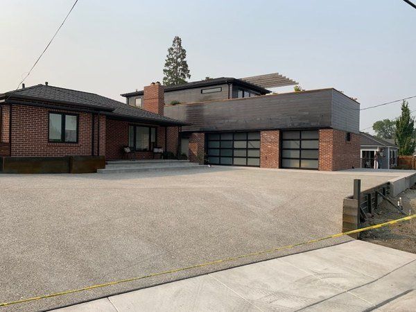 A large brick house with a concrete driveway in front of it.