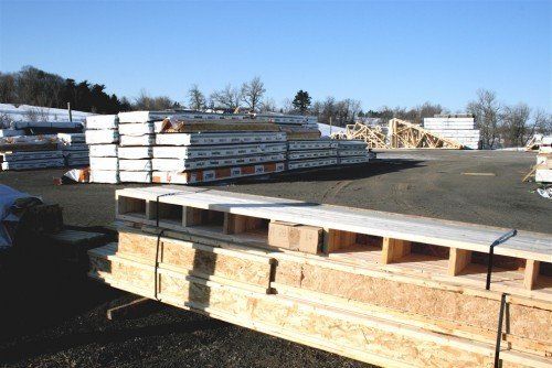 Des piles de bois dans un dépôt de matériaux de construction en plein air, par une journée ensoleillée.