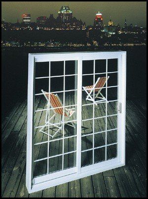 Porte coulissante en verre blanc à carreaux, deux chaises sur la terrasse, lumières de la ville en arrière-plan.