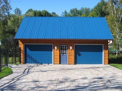 Garage double avec toit et portes bleus, bardage marron et allée pavée.