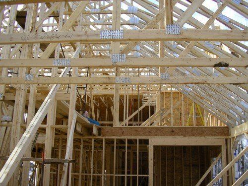 Charpente en bois d'une maison en construction, montrant les chevrons, les fermes et les montants des murs.