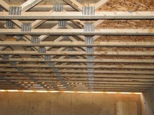 Des solives et des fermes en bois soutiennent un plafond en contreplaqué.