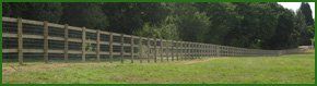 A long fence at the edge of a woods