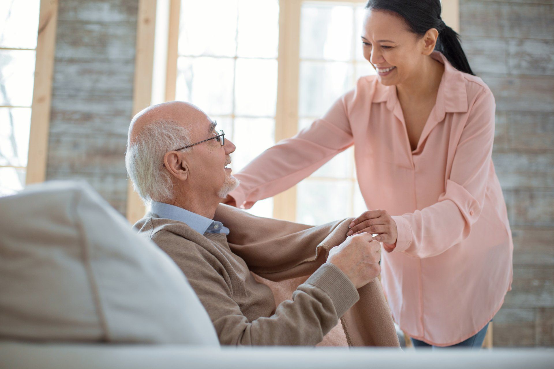 caregiver giving blanket to old man
